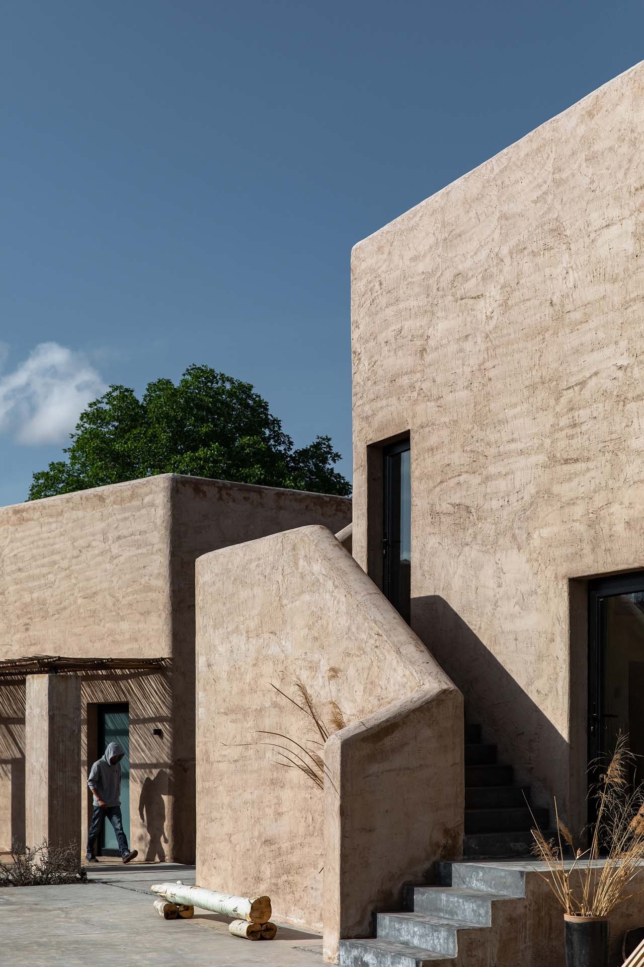 A guest walking beside the rammed-earth walls of Lost Villa