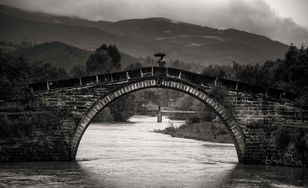 Shaxi's historic stone bridge crossing the river in misty monochrome