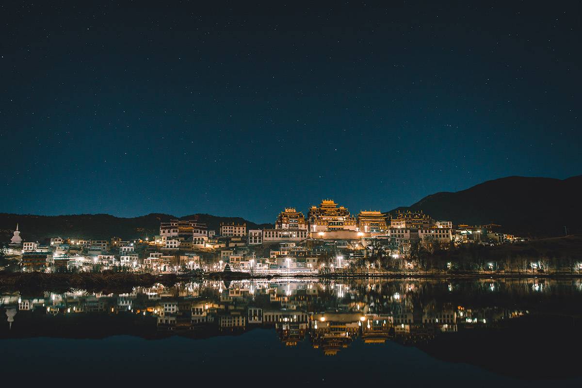 Songzanlin Monastery illuminated above its reflection in Lamuyangcuo Lake