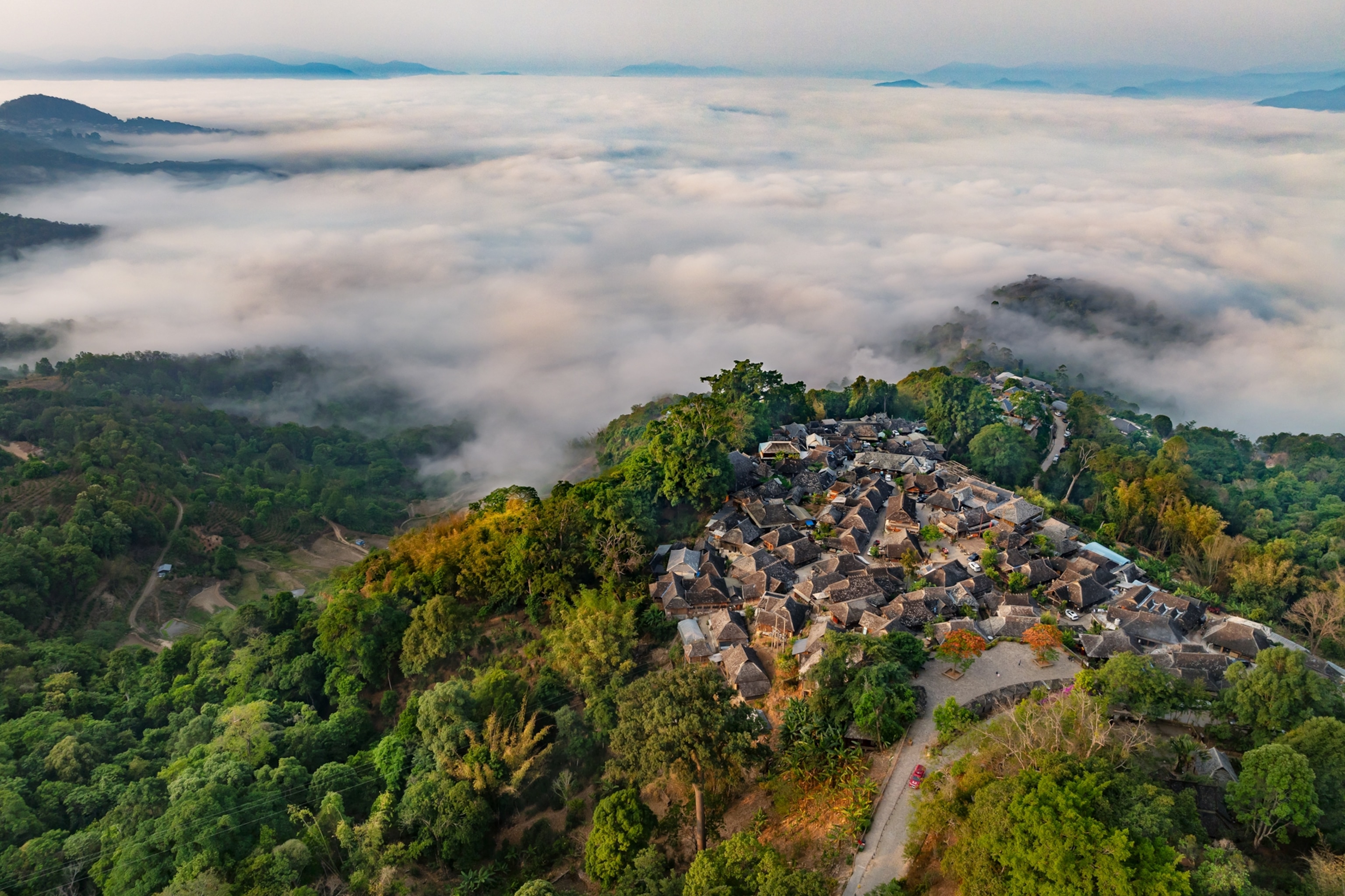 A tea village rising above cloud-filled forest on Jingmai Mountain