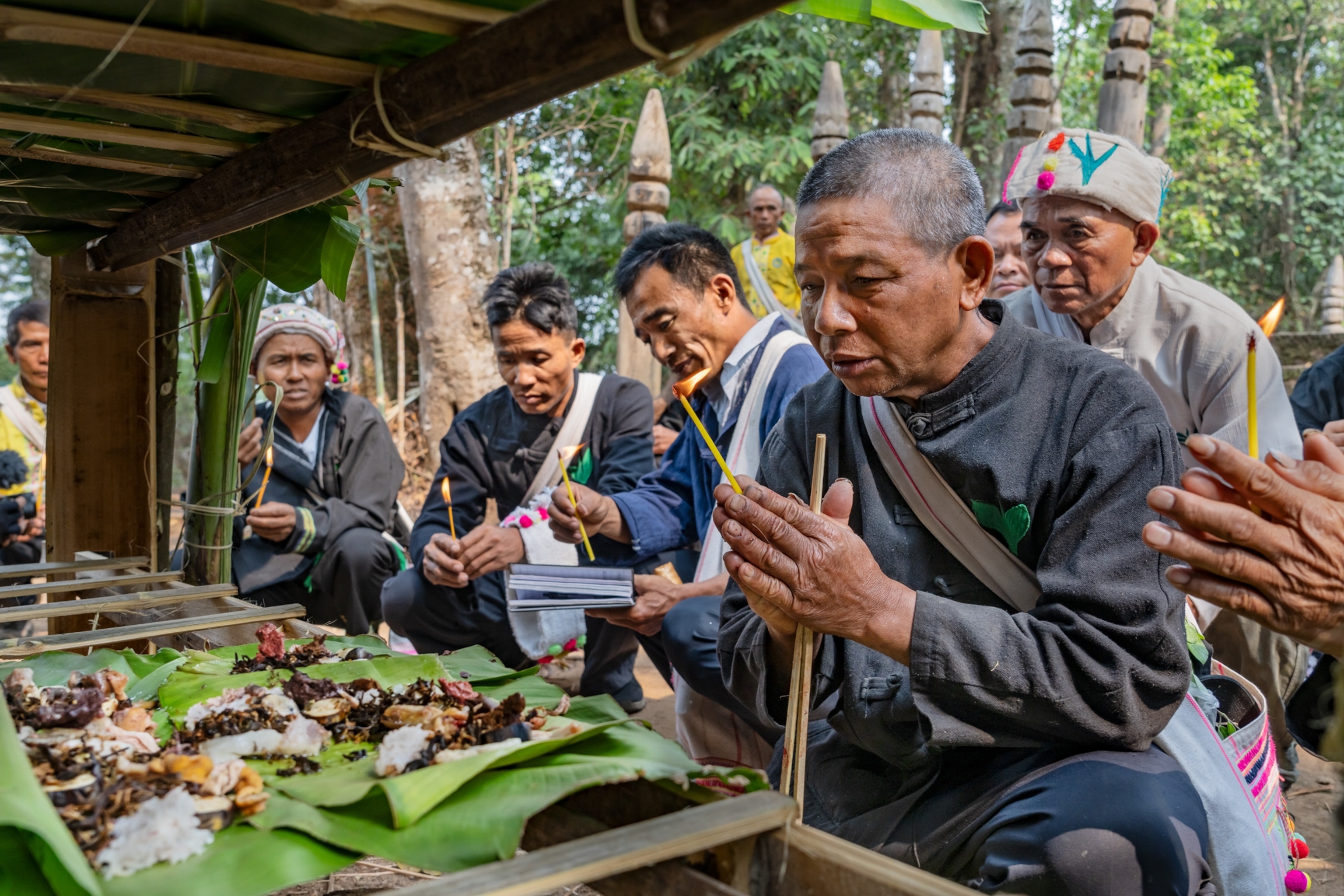 Blang tea growers praying over a candlelit food offering