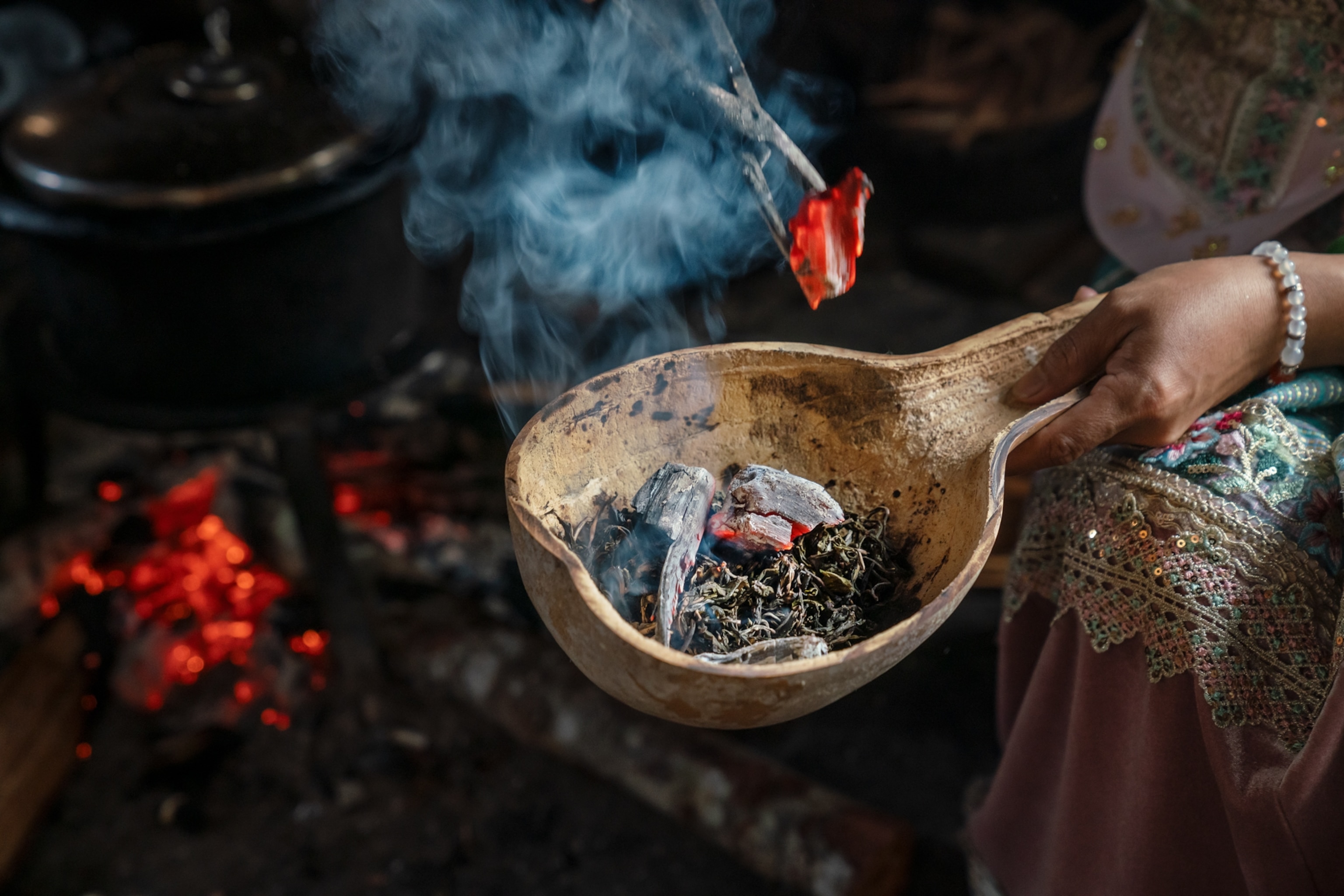 Raw Pu'er tea smoking over glowing embers in a wooden bowl