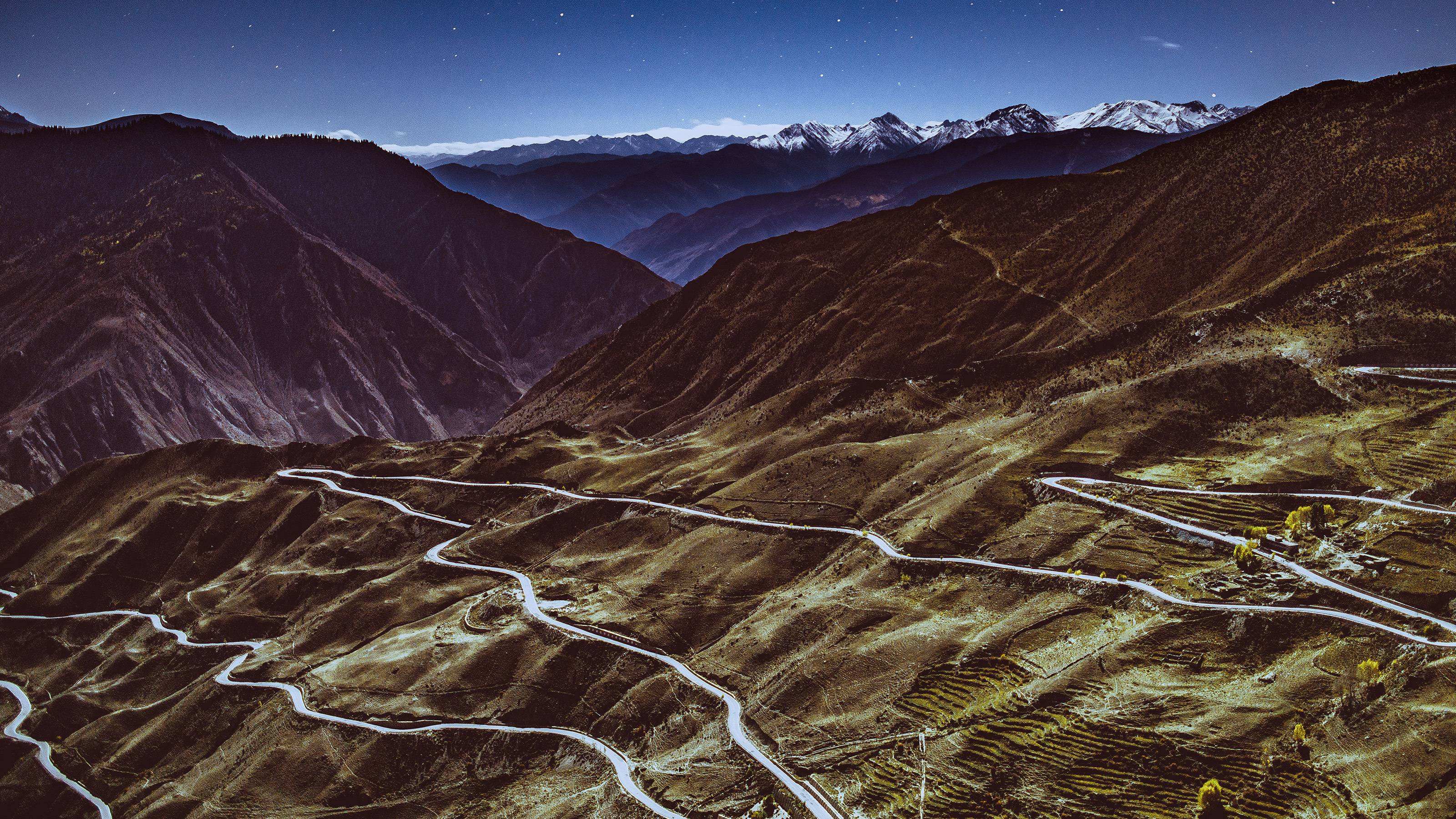 A moonlit road winding through the blue mountain valleys of Rumei